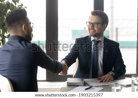 Smiling hr manager shaking hand of successful candidate after interview, Arabian man getting job, diverse business partners handshake, making great deal, agreement, employer greeting new employee Royalty-Free Stock Photo #1903215397