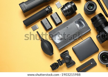 Flat lay composition with camera and video production equipment on yellow background. Space for text
