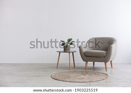 Modern interior design with light empty mock-up wall and gray furniture, loft and vintage of living room. Armchair, table with green plant in pot, round carpet on floor, on white wall background Royalty-Free Stock Photo #1903225519