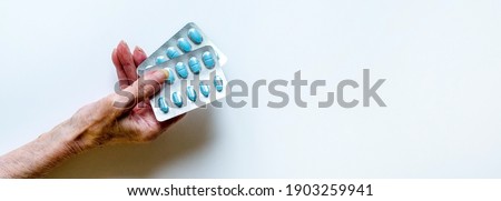 Elderly hands hold blisters of pills. Banner