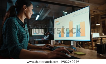 Young Handsome Project Manager Working on a Marketing Presentation on Desktop Computer in Busy Creative Office. Male Specialist is Implemeting Business Strategy Points Into the Keynote. Royalty-Free Stock Photo #1903260949