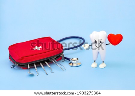 a cartoon model of a tooth with a heart in its hands and a first aid kit with dental instruments on a blue background. Love of oral hygiene