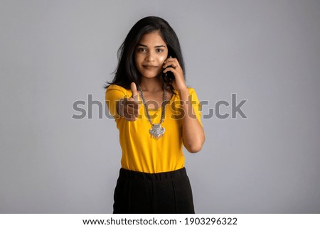 Young girl using mobile phone or smartphone on gray background