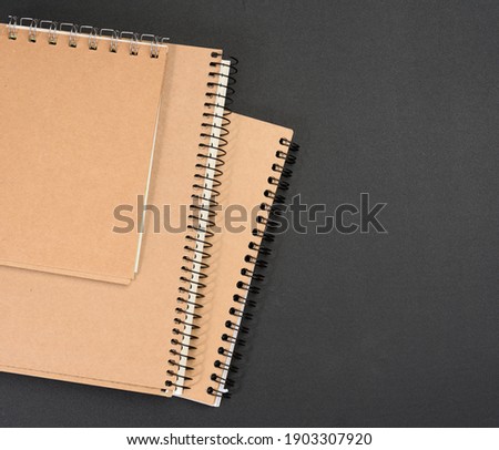 closed notepad with brown sheets on black background, close up