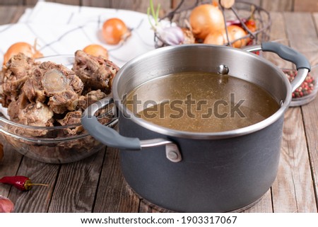Bone Broth Bouillon in Metal saucepan on the table, paleo diet
