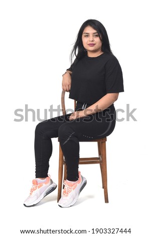 Latin woman wearing sportswear sitting sideways on white background. 