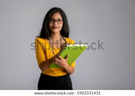 Pretty young girl posing with the book on grey background