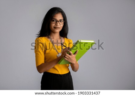 Pretty young girl posing with the book on grey background