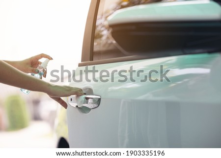 A woman spraying off her car door handle during the COVID-19 scare.