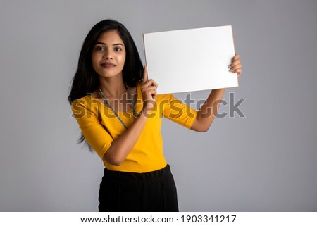 A young girl or businesswoman holding a signboard in her hands on a gray background.