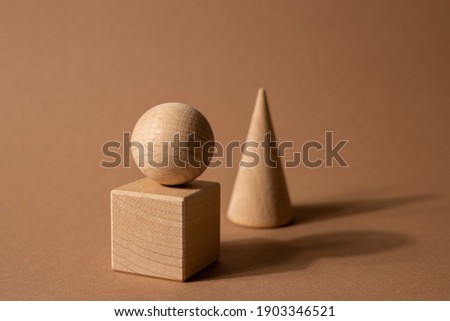 Wooden toy children's sorter with small wooden details in the form of geometric shapes rectangle, square, triangle on a brown background, figure concept with dark shadows side view