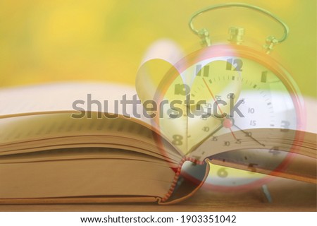 Overlapping pictures of open books form a heart on alarm clock background