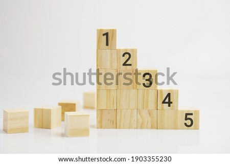 Selective focus of wooden blocks stacking as step up stair with number 5, 4, 3, 2, 1 arranged on stacks

. Business concept for growth success process and achievement concept.

