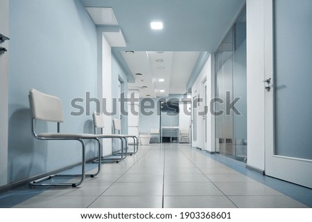 Empty modern hospital corridor, clinic hallway interior background with white chairs for patients waiting for doctor visit. Contemporary waiting room in medical office. Healthcare services concept Royalty-Free Stock Photo #1903368601