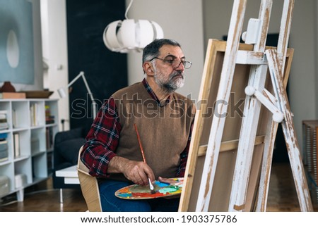 senior man painting the picture at his home