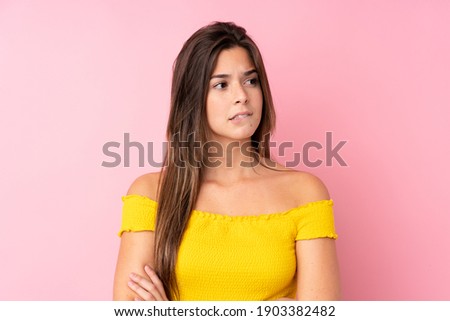 Teenager Brazilian girl over isolated pink background with confuse face expression