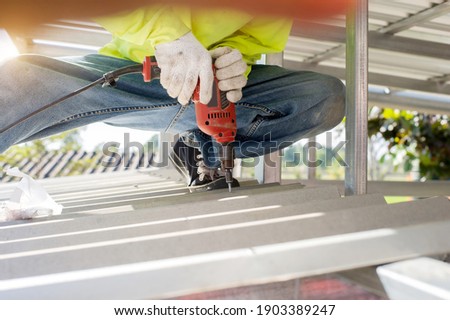 Construction worker install new roof,Roofing tools,Electric drill used on new roofs with Metal Sheet. Royalty-Free Stock Photo #1903389247