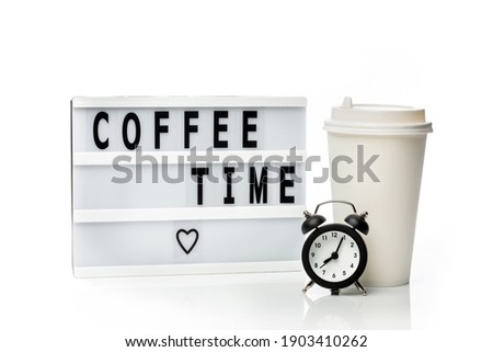 Light box with the inscription "Coffee Time" next to a coffee cup and an alarm clock isolated on a white background. Takeaway coffee concept.