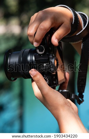 Woman hands holding a digital camera with blue and green background