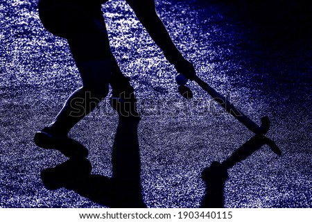 Field Hockey player, ready to pass the ball to a team mate. Blue color filter