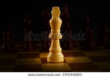 A Chess game board with a spotlighted King against the opponents army.