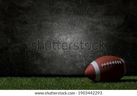 American football on green grass, on dark background. Team sport concept Royalty-Free Stock Photo #1903442293