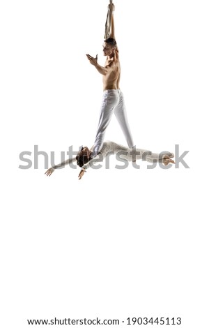 Lovely. Couple of acrobats, circus athletes isolated on white studio background. Training perfect balanced in flight, rhythmic gymnastics artists practicing with equipment. Grace in performance.