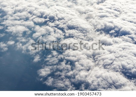 An aerial view above cloud cover shows the texture of the clouds.