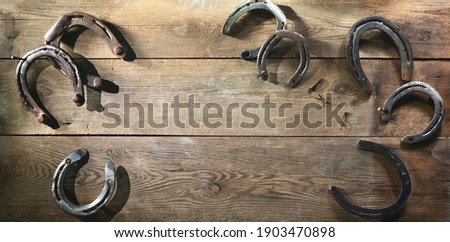 Old rusty horse shoes lying on a wooden barn floor Royalty-Free Stock Photo #1903470898