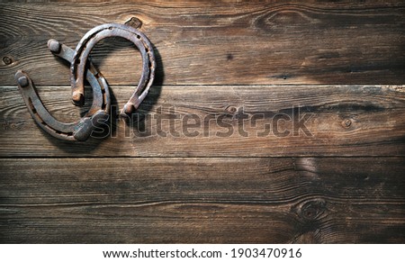 Two old rusty horse shoes as symbol for lucky charm on rustic wooden background