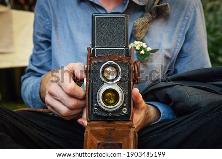 Close up portrait of man holding vintage camera. Retro Shooting.