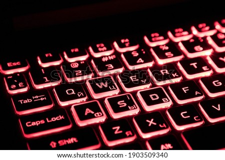 Laptop keyboard glowing with red light in the dark. Computer keyboard with backlighting. Technologies. Computer buttons. Isolated objects.