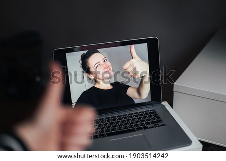 Young woman shows a thumb up from a laptop's screen. Online video call with a girl Royalty-Free Stock Photo #1903514242