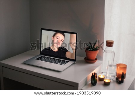 Online video call with a young woman from a laptop. Grey laptop on a table with candles, water, romantic atmosphere. Concept of relationship during pandemic  Royalty-Free Stock Photo #1903519090