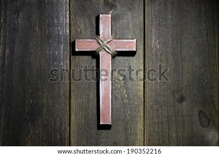 Spotlight on hanging wooden cross on old rustic antique wood background; Easter, Christmas, Memorial Day and religious background with copy space
