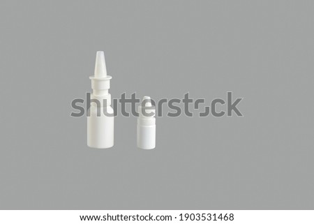 Blank Medicine bottle. White plastic medical containers for nasal spray (decongestant) on gray background, mockup. Pharmacy business and treatment concept. Copy space. Close-up.