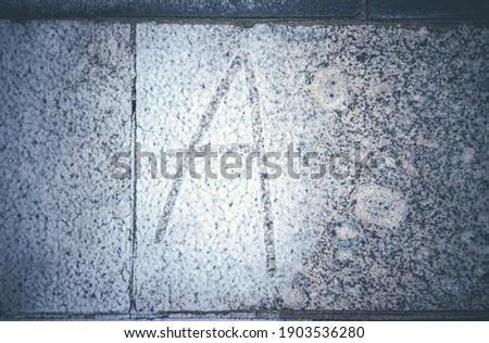 The letter A is written on the icy granite wall, white frost.