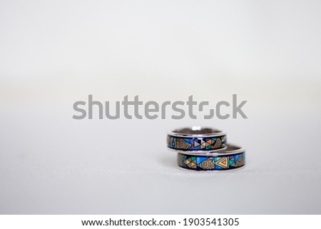 Macro picture of two beautiful wedding rings with colorful blue enamel pattern, isolated, white background