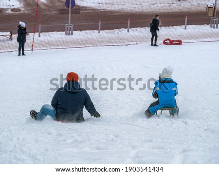 Parents with their Children having fun sledding in the snow