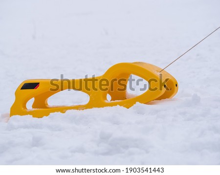A yellow plastic sledge or sleigh sliding on the snow