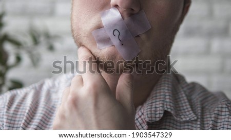 A man with a plaster over his mouth, a man with a closed mouth with adhesive tape