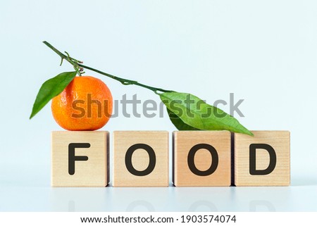 Word food on wooden blocks on white background with tangerine. Healthy food concept or mandarin sale season