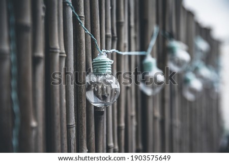 LED mint color light bulbs with wires hanging on a bamboo screen wall outside on a deck