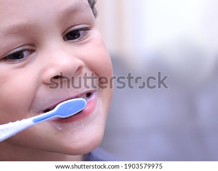 boy brushing his teeth with an electric tooth brush on grey background stock photo 