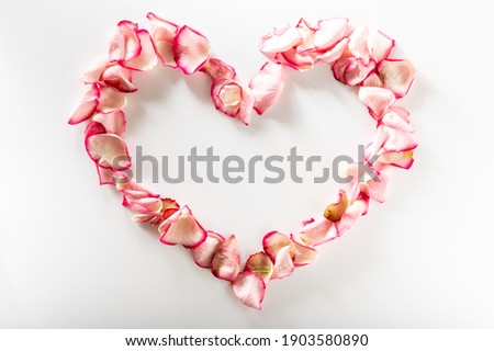 Heart shaped rose petals. Heart made of flowers on a white background.