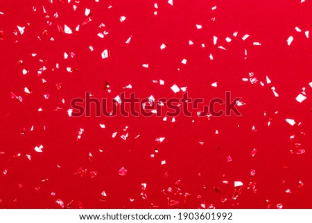 Beautiful festive red background with metallic shaped confetti. Holiday decoration concept.