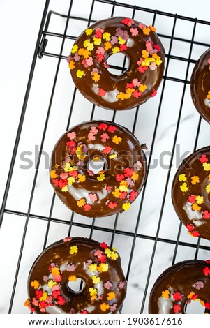 chocolate frosted donuts with fall colored sprinkles on a cooling rack
