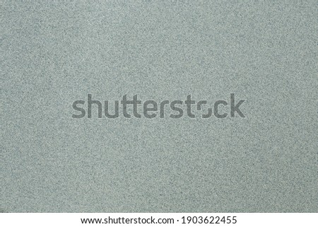 A macro shot of a primarily cool toned green background with gray and white speckling.