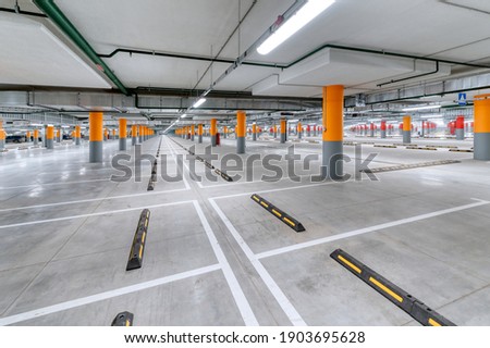 Large underground parking for cars. Empty new parking lot with cement floor.
