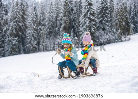 Children on a wooden sled on a winter day. Active winter kids outdoors games